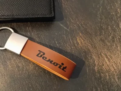 Porte-clé en cuir camel avec anneau d'attache en nickel argenté posé sur une table en bois noir -Pau de Cuir-Pau-Maroquinerie artisanale