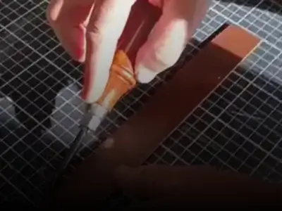 Mains d'un homme qui realise une ceinture en cuir brun-Pau de Cuir-Pau-Maroquinerie artisanale