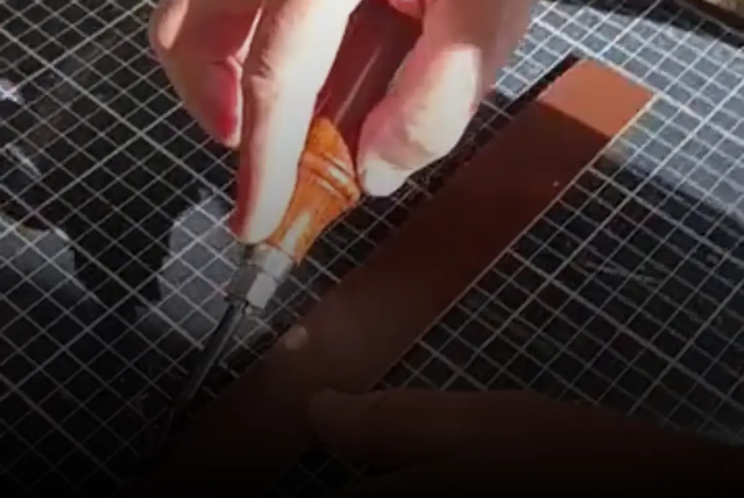 Mains d'un homme qui realise une ceinture en cuir brun-Pau de Cuir-Pau-Maroquinerie artisanale