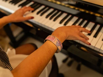 Mains de femme avec une manchette acier et cuir rose qui houent du piano-Pau de Cuir-Pau-Maroquinerie artisanale