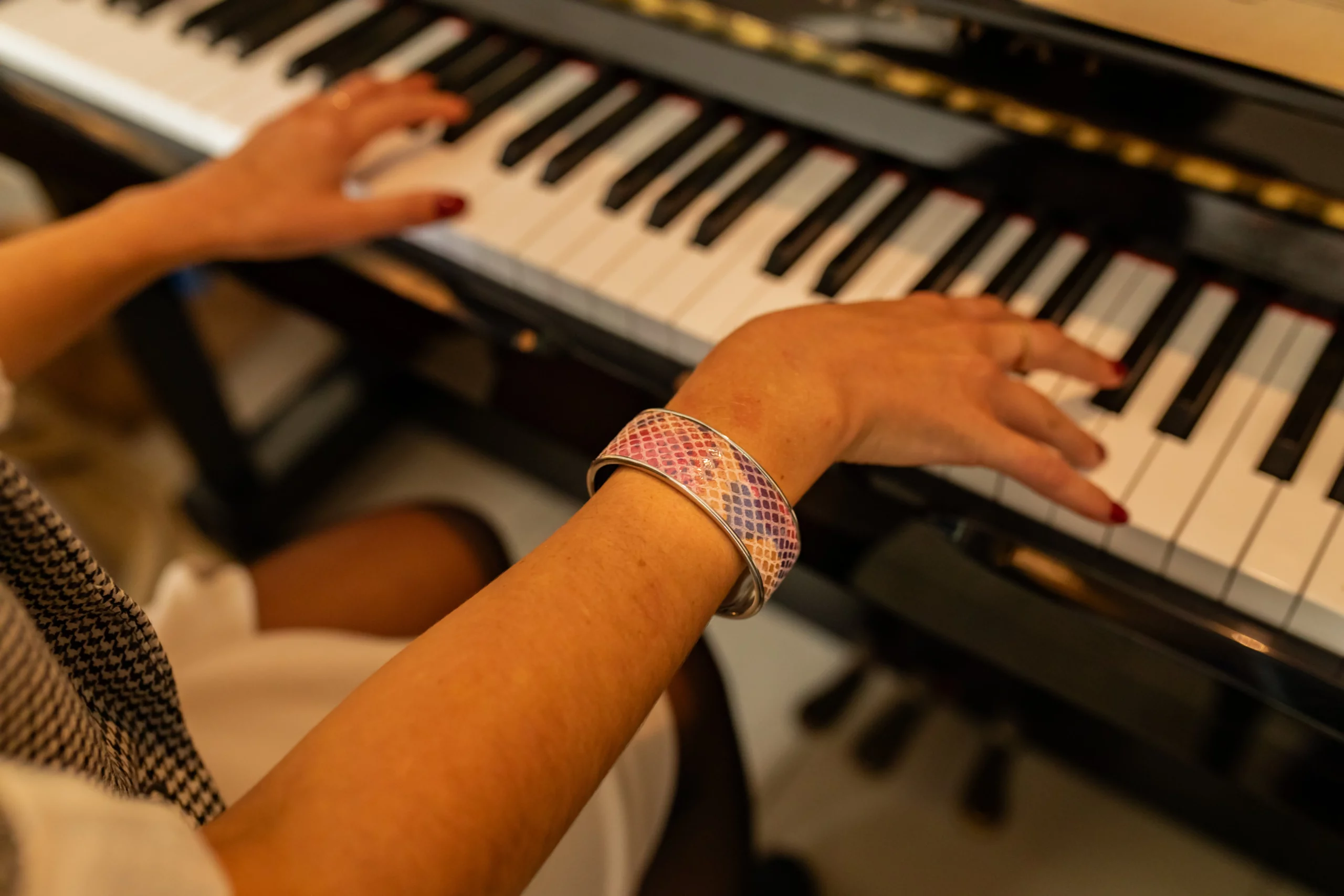 Mains de femme avec une manchette acier et cuir rose qui houent du piano-Pau de Cuir-Pau-Maroquinerie artisanale