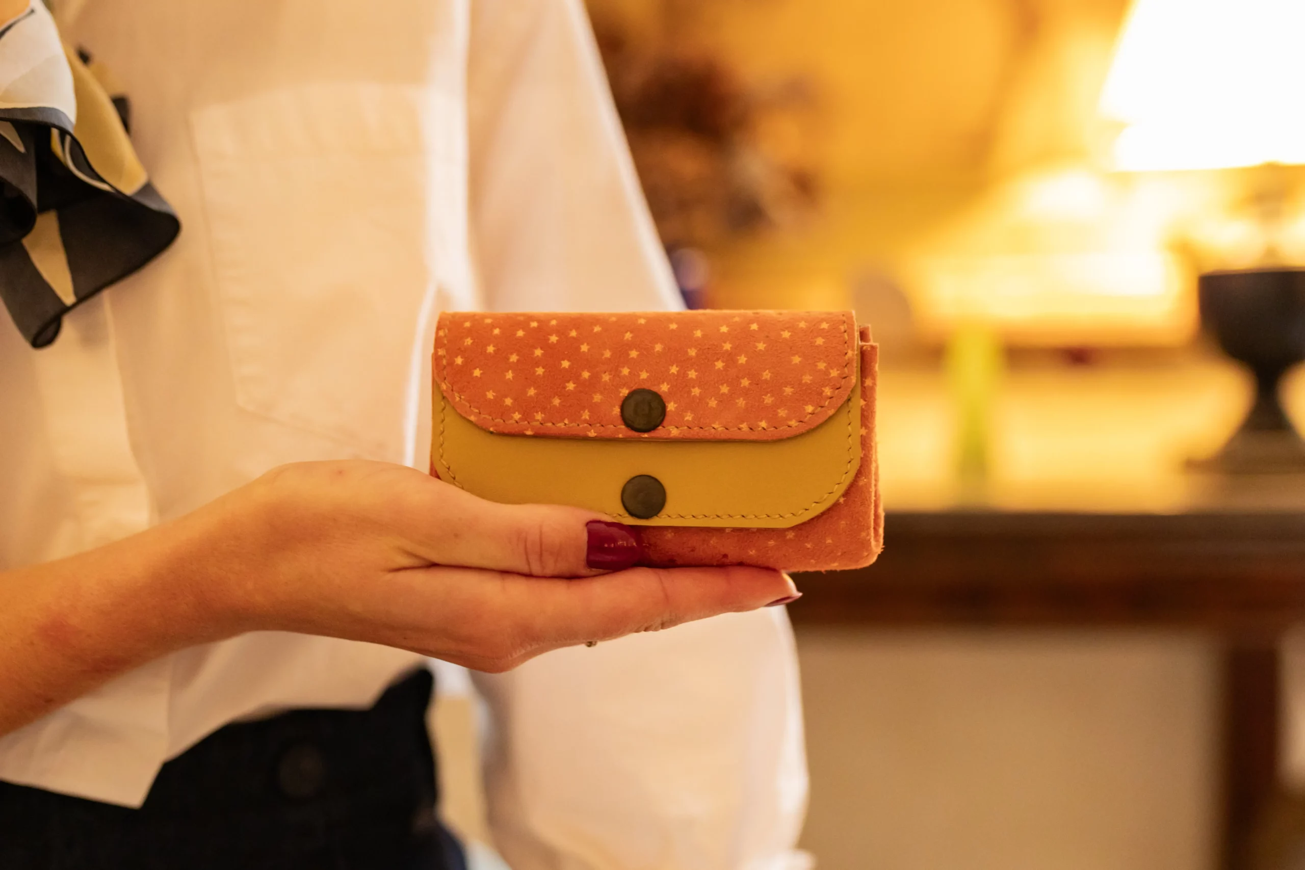 Porte-monnaie Le p'tit sucré cuir jaune moutarde et suédine orange avec des petites étoiles jaunes posé dans la main d'une femme-Pau de Cuir-Pau-Maroquinerie artisanale
