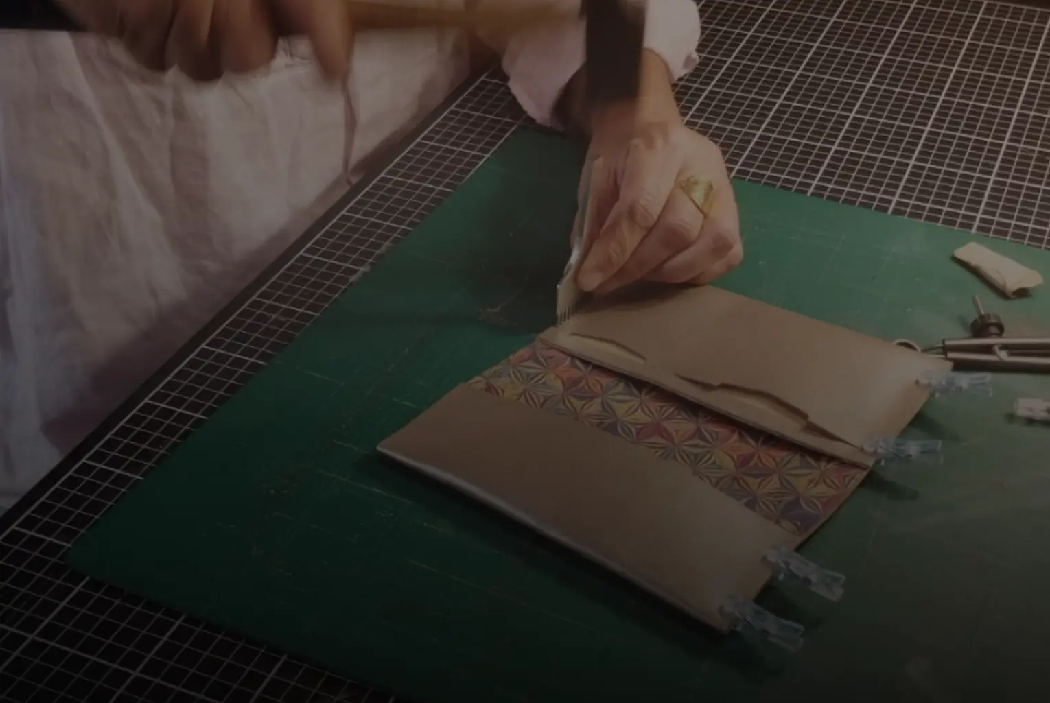 Mains de femme en train de travailler le cuir et créer un porte-chéquier en cuir beige irise, avec inserts pour la carte d'identite et la carte bancaire- Pau de cuir-Pau - Maroquinerie artisanale