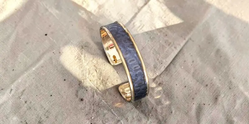 Manchette largeur moyenne laiton et cuir imprimé serpent bleu nuit-posé sur un coupon de lin naturel beige -pau-de cuir-pau- maroquinerie artisanale